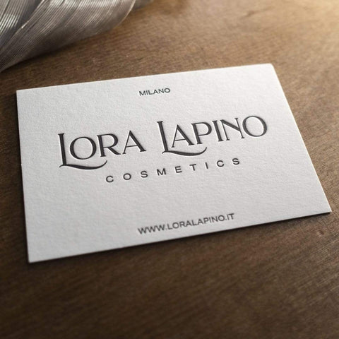 Eine geprägte Letterpress Visitenkarte mit feiner Haptik und spürbarem Druckbild. Schwarzer Druck auf naturweißem Papier. Beispiellogo "LORA LAPINO COSMETICS"  mit Ortsangabe und Internetseite.