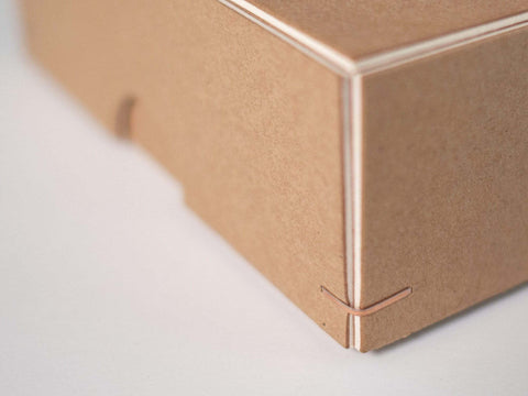 Handgefertigte Box aus Kraftkarton mit weißem Kern. Maße 12cm x 12cm x 4cm. Die kupferfarbene Drahtheftung an jeder Ecke verleihen der Box einen hochwertigen Look.
