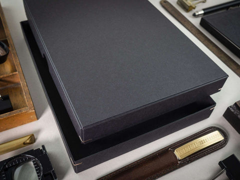 Handgefertigte schwarze Design Box inszeniert mit anderen Werkstatt- und Büroartikeln. Maße 19cm x 13cm x 2,5cm. Die Drahtheftung an jeder Ecke verleiht der Box einen hochwertigen Look.