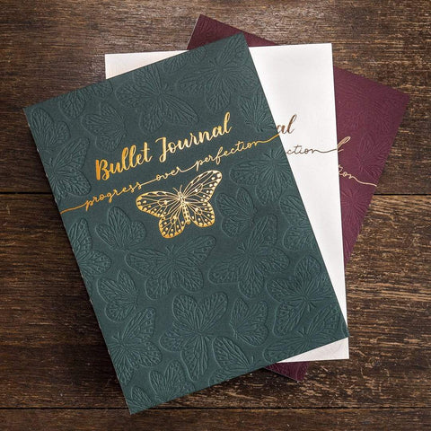 Drei Letterpress Bullet Journals in den Farben Racing Green, Ivory Rosé und Claret. Mit kupferfarbener oder roségoldener Folienprägung. Schmetterlingsmuster als Blindprägung.